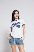 Woman wearing Malone shirt agains gray background.
