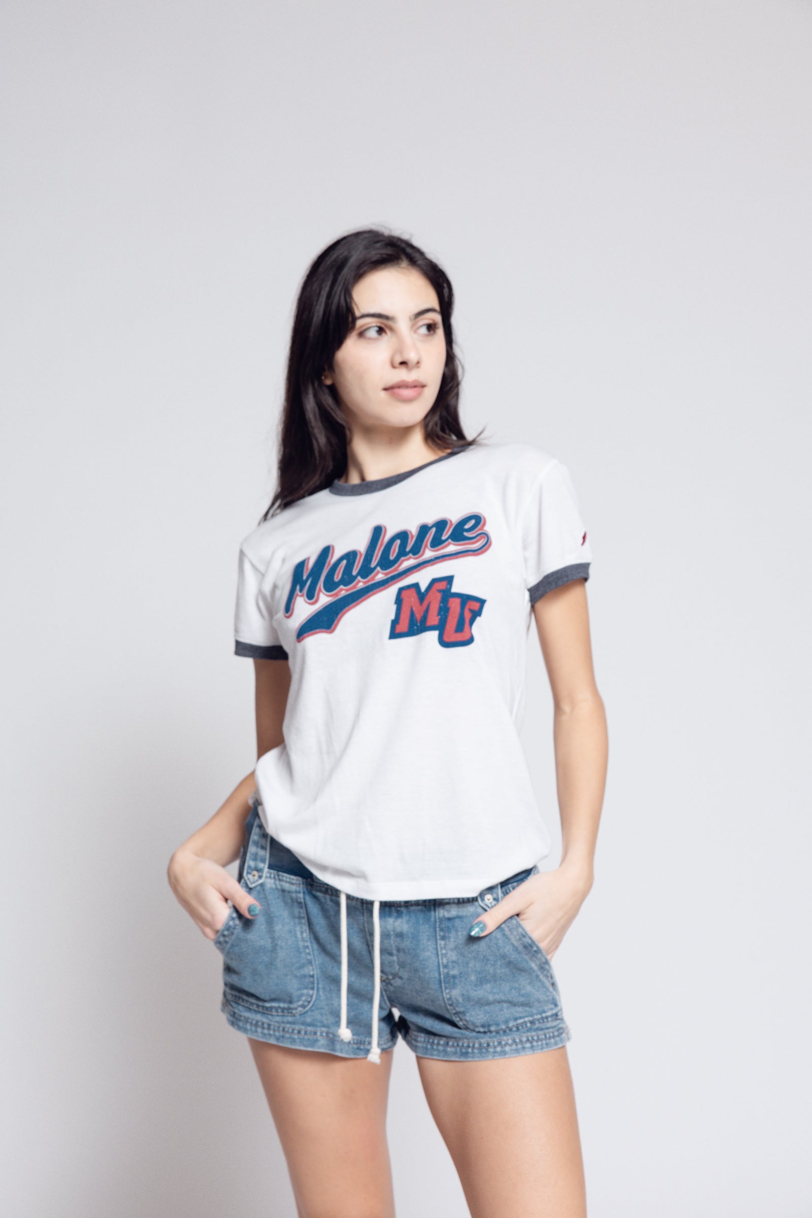 Woman wearing Malone shirt agains gray background.